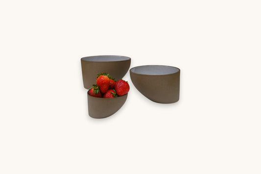 Three brown ceramic bowls with strawberries on a white background